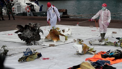 Workers spray disinfectant at parts of aircraft recovered from Java Sea where a Sriwijaya Air passenger jet crashed.