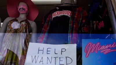 A 'Help Wanted,' sign is shown in the window of a souvenir shop, Thursday, Jan. 7, 2021, in Miami Beach, Fla. Layoffs spiked in November compared with the previous month and the number of job openings slipped, a sign the job market has stalled as the resurgent coronavirus has forced new shutdowns of restaurants and bars and discouraged consumer spending.