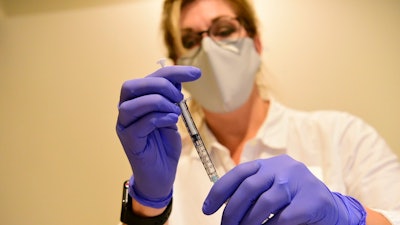 This Sept. 2020 photo provided by Johnson & Johnson shows a clinician preparing to administer investigational Janssen COVID-19 vaccine.