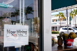 A 'Now Hiring,' sign is shown in the window of a restaurant in Miami Beach, Fla. America's employers likely cut back on hiring last month, and may have even shed jobs, as the economy suffers from a resurgent virus.