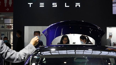 In this Sunday, Sept. 27, 2020, file photo, attendees wearing masks to protect from the coronavirus look at cars at the Tesla booth during the Auto China 2020 show in Beijing. Tesla Inc. is balking at recalling about 159,000 vehicles with potentially defective touch screens, so U.S. safety regulators are moving to force the company to take action, in news announced Wednesday, Jan. 13, 2021.