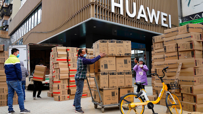Workers move boxes of computers on a street in Wuhan, China, Jan. 16, 2021.