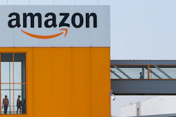 In this April 9, 2020 photo, employees observe social distancing due to coronavirus, at the entrance of Amazon, in Douai, northern France.