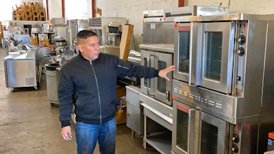 Jose Bonilla Jr. shows a used industrial oven for sale in the warehouse of his family's business, American Restaurant Supply in San Leandro, CA on Jan. 14.