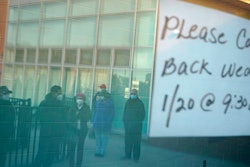 People waiting in line are reflected in the windows of a vaccination site in Paterson, N.J., Jan. 19, 2021.