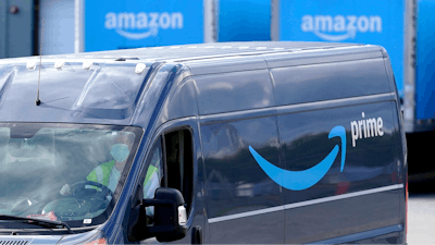 In this file photo, an Amazon Prime logo appears on the side of a delivery van as it departs an Amazon Warehouse location in Dedham, Mass.