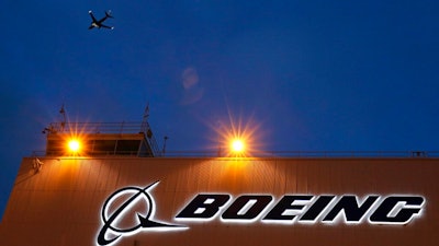 In this Oct. 19, 2015, file photo, an airplane flies over a sign at Boeing's newly expanded 737 delivery center at Boeing Field in Seattle. Federal regulators have imposed $5.4 million in civil penalties against Boeing on Thursday, Feb. 25, 2021, for violating terms of a $12 million settlement in 2015, and the aircraft maker has agreed to pay another $1.21 million to settle two current enforcement cases.