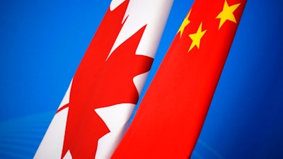 In this Nov. 12, 2018, file photo, flags of Canada and China are placed for the first China-Canada economic and financial strategy dialogue in Beijing, China. China says it has lodged a formal complaint with Canada over T-shirts ordered by one of the country’s Beijing Embassy staff that allegedly mocked China’s response to the coronavirus outbreak.