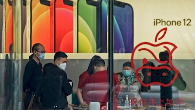 People wearing face masks to help curb the spread of the coronavirus look at iPad devices at an Apple store at the capital city's popular shopping mall in Beijing on Wednesday, Feb. 24, 2021. China’s commerce minister appealed to Washington for “join efforts” revive trade but gave no indication Wednesday when tariff war talks might resume or whether Beijing might offer concessions.