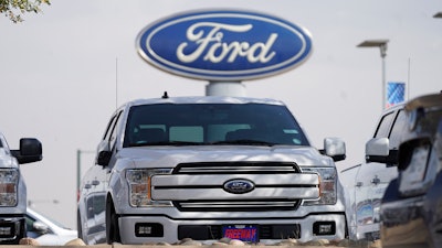 In this file photo vehicles sit at a dealership in Denver. Ford Motor Co. lost $1.28 billion last year as it dealt with the coronavirus pandemic.