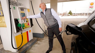 Jeremy Heskett, of Boston, prepares to pour gasoline at a Shell gas station, Thursday, Feb. 18, 2021, in Westwood, Mass. A deep freeze in the Gulf state region and beyond that killed dozens of people, left millions without power and jeopardized drinking water systems also forced as many as 11 refineries offline. The resulting capacity cuts could drive gas prices up by about 10 to 20 cents per gallon, said Patrick DeHaan, petroleum analyst at the travel app GasBuddy.