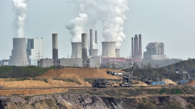 In this file photo, giant machines dig for brown coal at the open-cast mining Garzweiler in front of a smoking power plant near the city of Grevenbroich in western Germany.