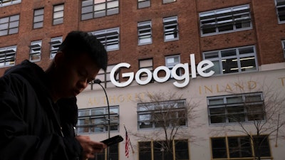 In this Dec. 17, 2018, file photo a man using a mobile phone walks past Google offices in New York. Google is closing the internal studio tasked with developing games for its Stadia cloud-gaming service, a move that raises questions about the future of its Stadia service itself. Google launched Stadia in November 2019 as a cloud-based gaming service, in deliberate contrast to pricey video-game consoles. But Google said Monday, Feb. 1, 2021 it will no longer invest in creating its own games for the service beyond any planned, near-term titles.