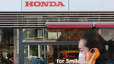 A woman wearing a face mask walks in front of a Honda Motor Co. showroom in Tokyo, Tuesday, Feb. 9, 2021. Japanese automaker Honda reported Tuesday its fiscal third quarter profit more than doubled to 284 billion yen ($2.7 billion) despite the coronavirus pandemic as auto sales grew in Japan and the U.S.