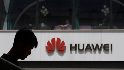 In this Thursday, May 16, 2019 file photo, a man is silhouetted near the Huawei logo in Beijing. Huawei took U.K. bank HSBC to court on Friday, Feb. 12, 2021 seeking documents the Chinese company says are key to its legal efforts to stop its chief financial officer from being extradited to the U.S. from Canada.