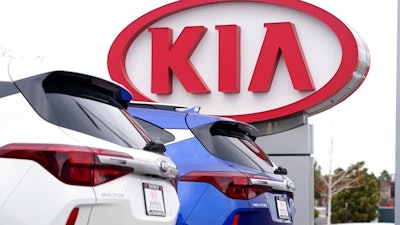 In this Sunday, Dec. 20, 2020, file photo the company sign stands over a row of unsold 2021 Seltos models at a Kia dealership, in Centennial, Colo. Kia Motors America says it’s restoring services crippled by a computer network outage that began Saturday, Feb. 13, 2021, and which apparently affected dealers’ ability to order vehicles and parts and knocked offline a smartphone app that owners use to remotely start and warm up vehicles.