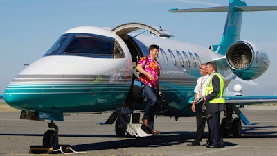 This Aug. 17, 2011 file photo, Jaeger Mah, left, is greeted by Vancouver International Airport CEO Larry Berg, right, and pilot Brent Fishlock as he steps off a Learjet upon arrival at the airport after a short tour in Richmond, B.C. The iconic Learjet, which carried generations of business executives and was made famous in pop songs, is about to fade into aviation history. Canada’s Bombardier said Thursday, Feb. 11, 2021 it will end production of the Learjet later this year.