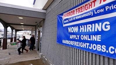 In this Dec. 10, 2020 file photo, a 'Now Hiring' sign hangs on the front wall of a Harbor Freight Tools store in Manchester, N.H. U.S. employers cut back sharply on hiring in December, particularly in pandemic-hit industries such as restaurants and hotels, as soaring virus infections and government restrictions weakened the economy that month. The number of available jobs rose slightly and layoffs fell, according to the Labor Department’s Tuesday report, known as the Job Openings and Labor Turnover Survey, or JOLTS.