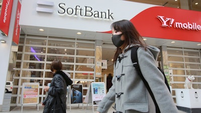 People walk by a SoftBank shop in Tokyo. Japanese telecommunications and technology conglomerate Softbank Group Corp. reported an $11 billion profit for the October-December quarter as its investments rose in value.