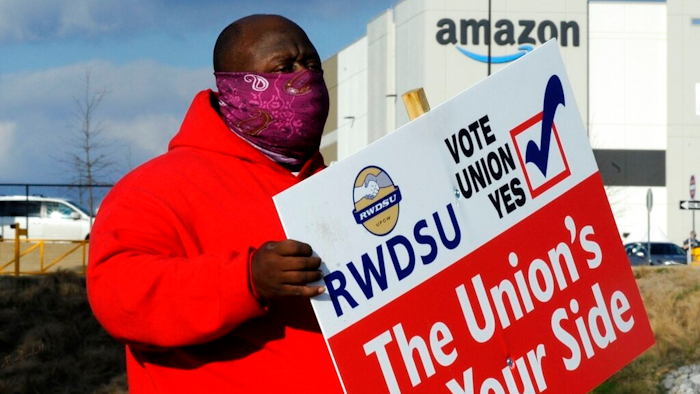 In this Feb. 9 file photo, Michael Foster of the Retail, Wholesale and Department Store Union holds a sign outside an Amazon facility where labor is trying to organize workers in Bessemer, Ala.