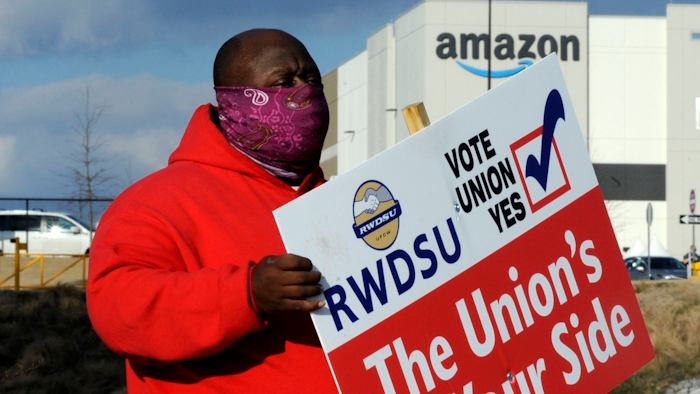In this file photo, Michael Foster of the Retail, Wholesale and Department Store Union holds a sign outside an Amazon facility in Bessemer, Alabama.