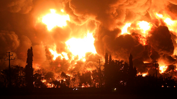 Cars pass by as fire razes through Pertamina Balongan Refinery in Indramayu, West Java, Indonesia, early Monday, March 29, 2021. Hundreds of people were evacuated from a nearby village after the massive fire broke out at the refinery.
