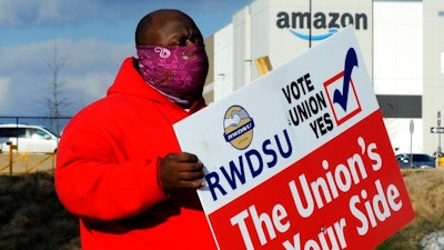 In this Feb. 9 file photo, Michael Foster of the Retail, Wholesale and Department Store Union holds a sign outside an Amazon facility where labor is trying to organize workers in Bessemer, Ala.