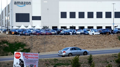 This Feb. 9, 2021 photo file photo, a car enters an Amazon facility where labor is trying to organize workers in Bessemer, Ala. Organizers are pushing for some 6,000 Amazon workers to join the Retail, Wholesale and Department Store Union on the promise it will lead to better working conditions, better pay and more respect. Amazon is pushing back, arguing that it already offers more than twice the minimum wage in Alabama and workers get such benefits as health care, vision and dental insurance without paying union dues.