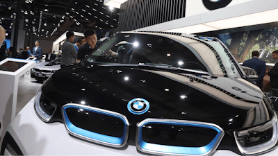 In this file photo, a worker cleans an electric vehicle at the BMW booth during the Auto Shanghai show.