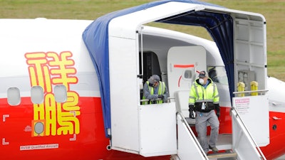 In this April 21, 2020, file photo, Boeing Co. workers wearing masks stand near an entry door to a 737 Max airplane owned by China-based Lucky Air, in Renton, Wash. China isn’t ready to join the United States in approving Boeing’s 737 Max to return to flying following a two-year grounding prompted by a pair of fatal crashes, a regulator said Monday, March 1, 2021.