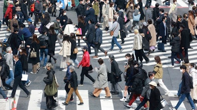 People wearing face masks to protect against the spread of the coronavirus cross a scramble intersection in Tokyo, Tuesday, March 9, 2021.