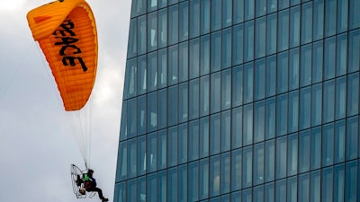 An activist of environmental organization Greenpeace flies with a motorized paraglider past the European Central Bank in Frankfurt, Germany, Wednesday, March 10, 2021. Two activists landed on the roof of a side building and unrolled a banner to protest against the ECB's climate policy.