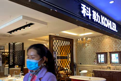 A woman wearing a face mask walks by Kohler shop inside a mall selling bathroom fixtures in Beijing.