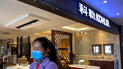 A woman wearing a face mask walks by Kohler shop inside a mall selling bathroom fixtures in Beijing.