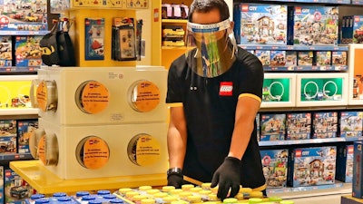 In this Monday, June 15, 2020 file photo, an employee wearing protective gear arrange boxes of Lego at a toy store at the Senayan City, in Jakarta, Indonesia. Sales of Lego sets surged in 2020 as more children stayed home during global pandemic lockdowns - and parents bought the colorful plastic brick toys to keep them entertained during weeks of isolation. The privately-held Danish company said its net profit rose 19% to 9.9 billion kroner ($1.6 billion) as sales jumped 21% and it grew its presence in its 12 largest markets.