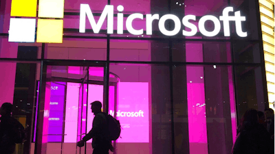In this Nov. 10, 2016, file photo, people walk past a Microsoft office in New York. China-based government hackers have exploited a bug in Microsoft's email server software to target U.S. organizations, the company said Tuesday, March 2, 2021.