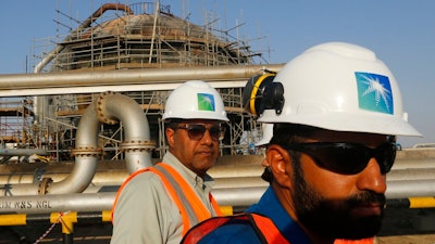 In this Sept. 20, 2019, file photo, engineers walk in front of an oil separator at a Saudi Aramco processing facility in Abqaiq, Saudi Arabia. Saudi Arabia's state-backed oil giant Aramco announced Sunday, March 21, 2021, that its 2020 profits fell sharply in 2020 to $49 billion, a big drop that came as the coronavirus pandemic roiled global energy markets.