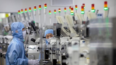 In this file photo, employees wearing protective equipment work at a semiconductor production facility for Renesas Electronics.
