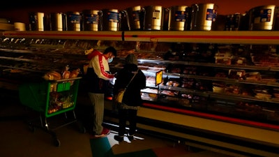 Texans shop in a dark supermarket after one of the worst blackouts in state history, February 2021.