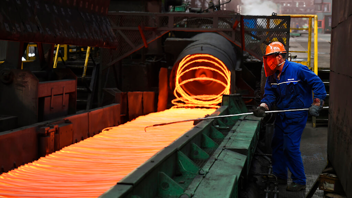 A worker manipulates coils of steel at Xiwang Special Steel, Zouping County, China, March 5, 2018.