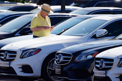 A shopper looks over a line of 2020 sedans at a Mercedes Benz dealership, Littleton, Colo., Oct. 4, 2020.