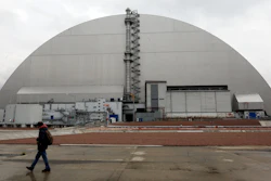 A man walks past a shelter covering the exploded reactor at the Chernobyl nuclear plant, Chernobyl, Ukraine, April 15, 2021.