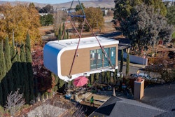This photo provided by Mighty Buildings shows a 3D-printed housing module being delivered. Most of the modules built by Mighty Buildings are assembled in the factory, transported by truck to the owner’s property, then put into place using a crane.