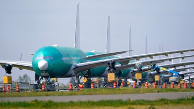 A line of Boeing 777X jets are parked nose to tail on an unused runway at Paine Field, near Boeing's massive production facility, Friday, April 23, 2021, in Everett, Wash. Boeing Co. on Wednesday, April 28, reported a loss of $537 million in its first quarter. The Chicago-based company said it had a loss of 92 cents per share. Losses, adjusted for non-recurring gains, were $1.53 per share.