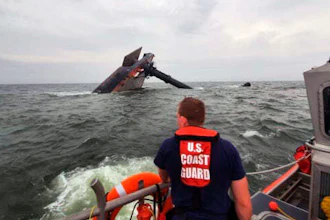 A Coast Guard Response Boat searches for survivors near the capsized SeaCor Power, an oil industry vessel.