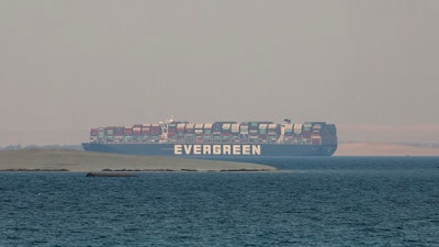 In this March 30, 2021 file photo, the Ever Given, a Panama-flagged cargo ship, is seen in Egypt's Great Bitter Lake. The Japanese owner of the massive container ship that blocked the Suez Canal for nearly a week, halting billions of dollars in maritime commerce, is asking owners of the freight it is carrying to share the cost of the damages demanded by Egyptian authorities.