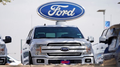 In this Sunday, Oct. 11, 2020, file photo, a row of 2020 sports-utility vehicles pickup trucks sits at a Ford dealership, in Denver. Ford Motor Co. says it made $3.26 billion in the first quarter, helped by rising vehicle prices and in spite of production cuts due to a global shortage of computer chips. The earnings reversed a nearly $2 billion net loss from a year ago, when Ford burned through cash at the start of the coronavirus pandemic.
