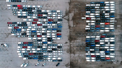 In this aerial photo, mid-sized pickup trucks and full-size vans are seen in a parking lot outside a General Motors assembly plant where they are produced Wednesday, March 24, 2021, in Wentzville, Mo. The global shortage of semiconductors is forcing General Motors to further cut production at six North American factories as chip supplies seem to be growing tighter. The shutdowns likely will crimp dealer inventory of vehicles made at the plants, but GM says it has managed to keep factories humming that make hot-selling and profitable full-size pickup trucks and SUVs.