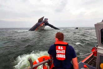 In this photo provided by the U.S. Coast Guard, A Coast Guard Station Grand Isle 45-foot Response Boat-medium boat crew member searches for survivors near the capsized SeaCor Power. The Seacor Power, an oil industry vessel, flipped over Tuesday, April 13, 2021 in a microburst of dangerous wind and high seas.
