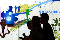 People pass by Samsung Electronics' shop in Seoul, South Korea, Wednesday, April 28, 2021. Samsung's founding family will donate tens of thousands of rare artworks, including Picassos and Dalis, and give hundreds of millions of dollars to medical research to help them pay a massive inheritance tax following last year's death of chairman Lee Kun-Hee.
